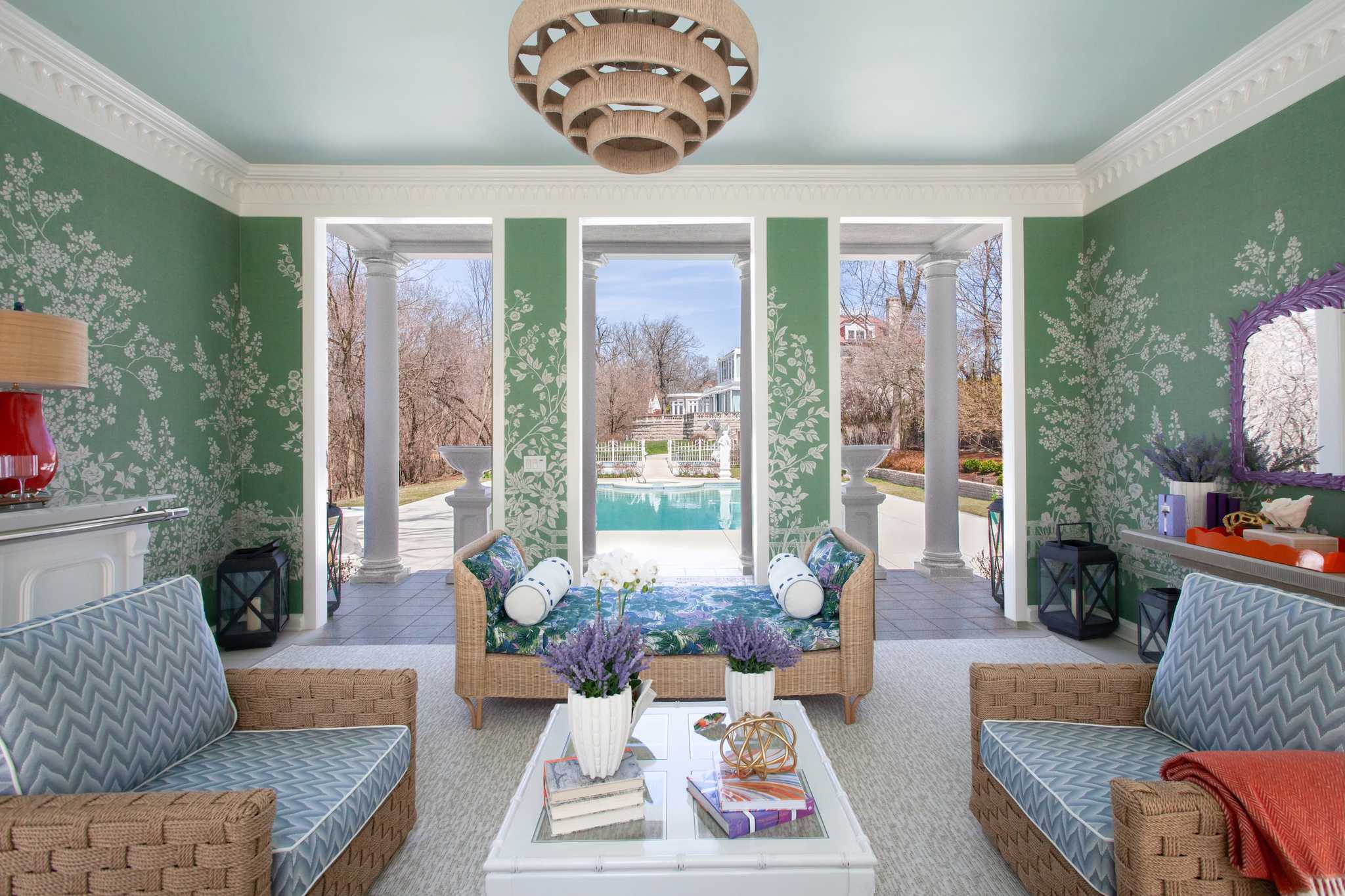 Living room with wicker furniture, floral-patterned walls, and a view of a pool.