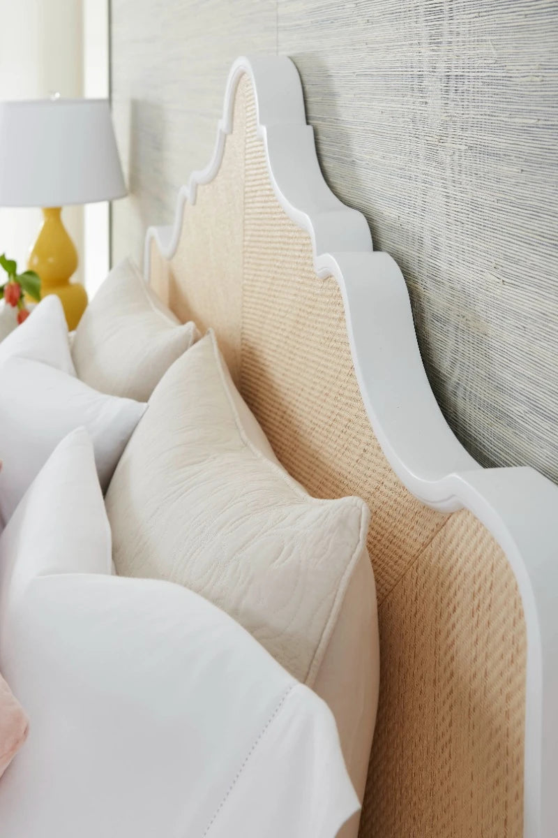 Close-up of a bed with decorative pillows and a textured headboard.